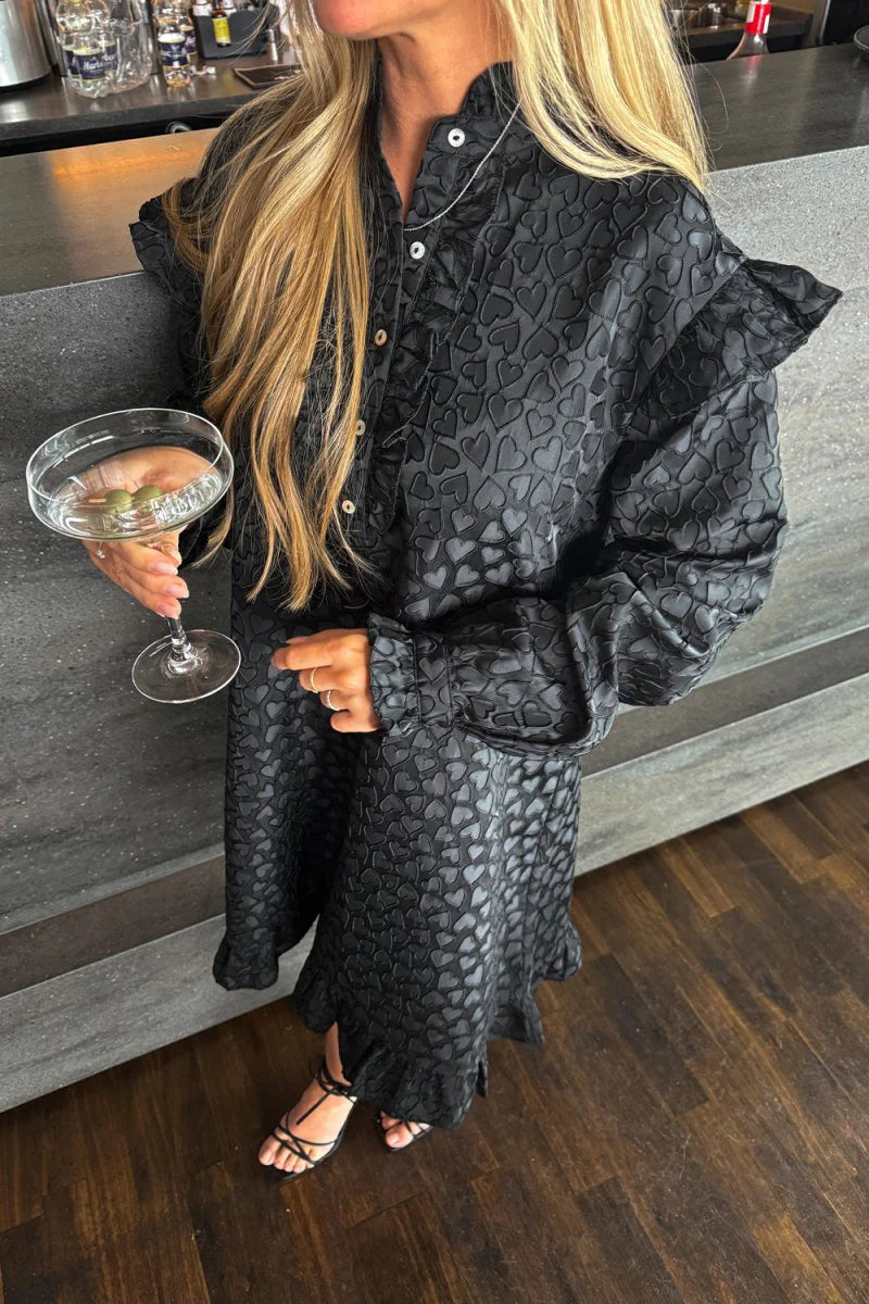 På billedet ser man en sort Noella kjole med hjerter, her bruges den som en cocktail kjole.