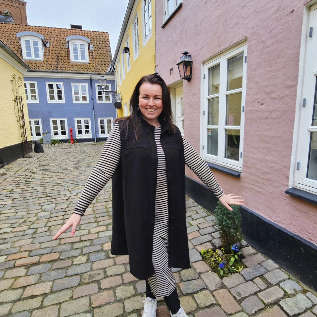 Ejeren af Diversita der står i et outfit fra Liberte inde i det man nok vil beskrive som en af de hyggeligste gader i Aalborg med alle de forskellig farvede huse.