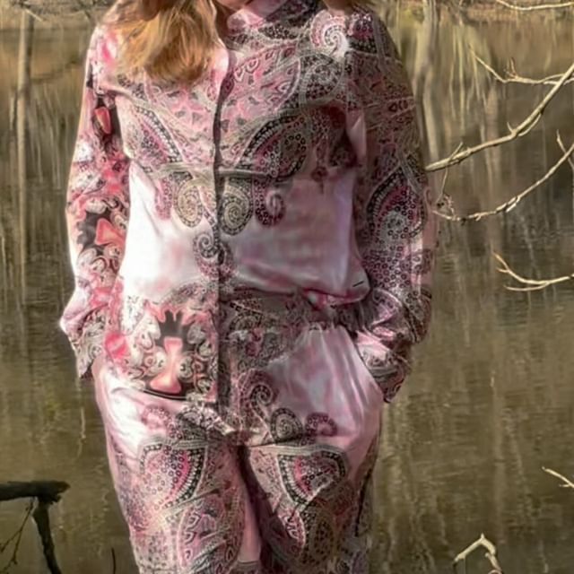 En kvinde der står ved en sø i et sæt fra Liberte Essentiel med mønstre og primære farver i lyserød, hvid og sort.